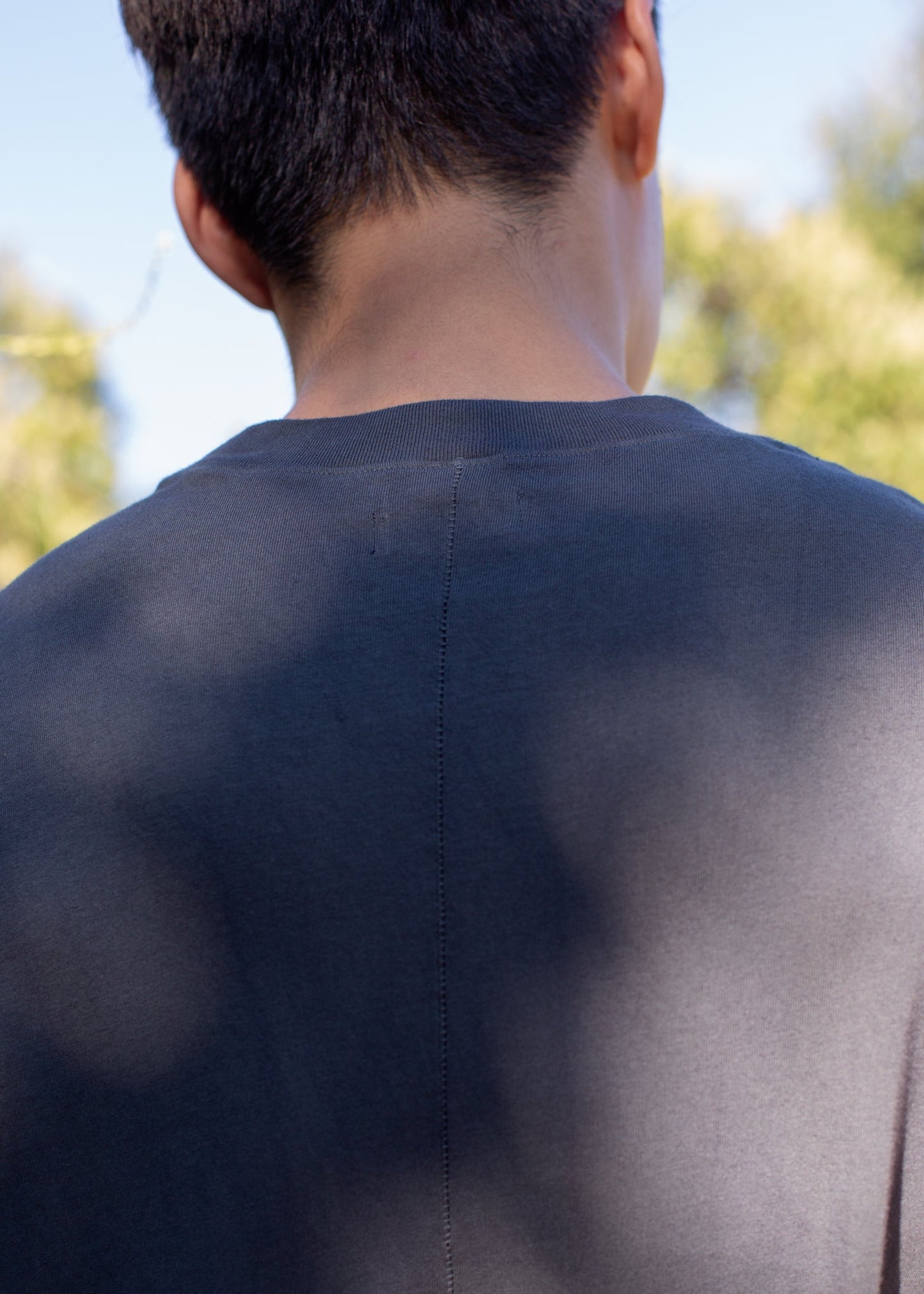 Back view of man wearing charcoal muscle tank outdoors, curated men's fashion on MANN