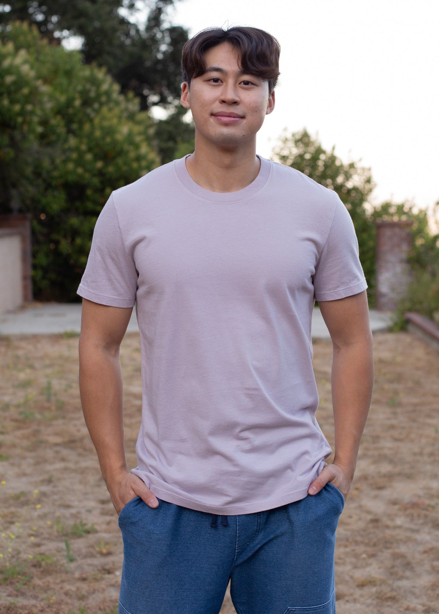 Man wearing organic lavender basic tee and blue shorts outdoors, men's casual fashion