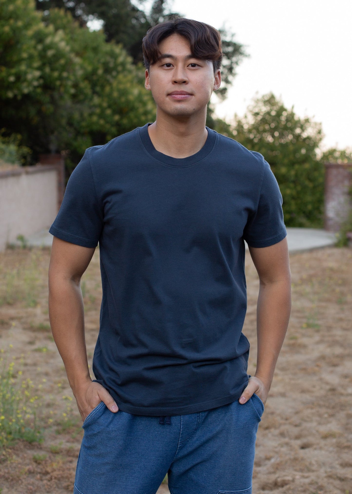 Man wearing an organic midnight blue basic tee and blue shorts outdoors, casual men’s fashion