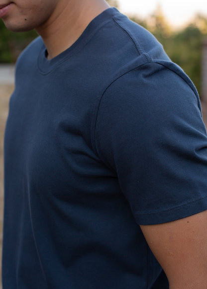 Man wearing organic basic navy tee outdoors, close-up, MANN men's fashion lifestyle