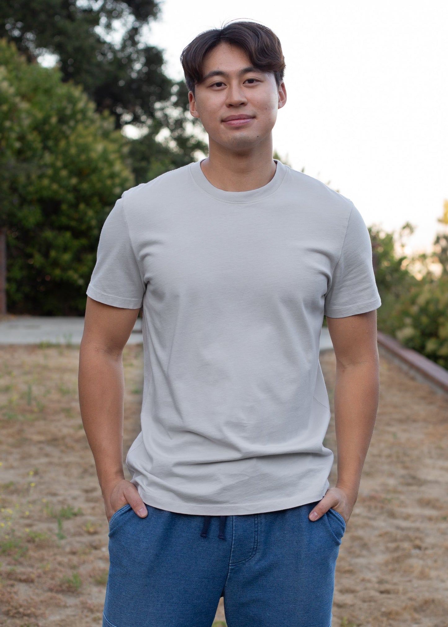 Man wearing organic slate basic tee and blue shorts outdoors, men's fashion lifestyle