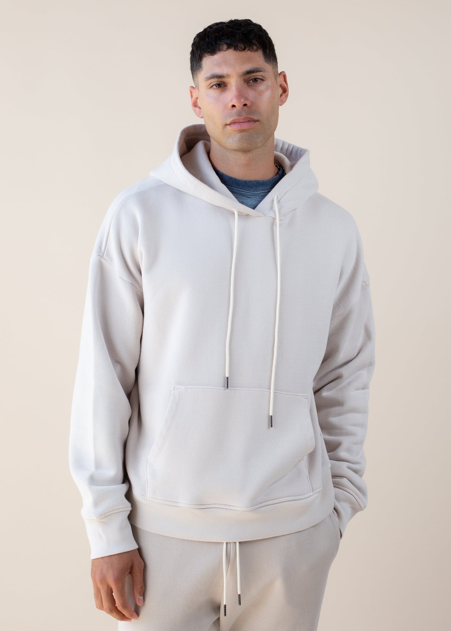 Man wearing cream hoodie and joggers, modern men's fashion, neutral background