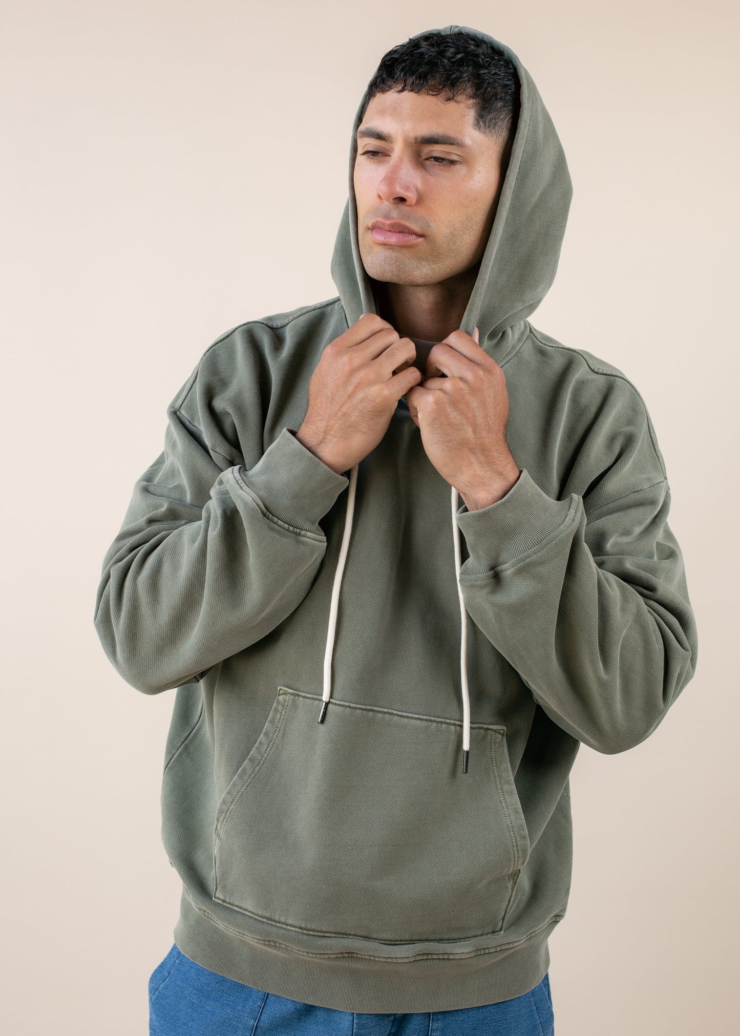 Man in green hoodie with drawstrings, posing against neutral background, men's fashion style