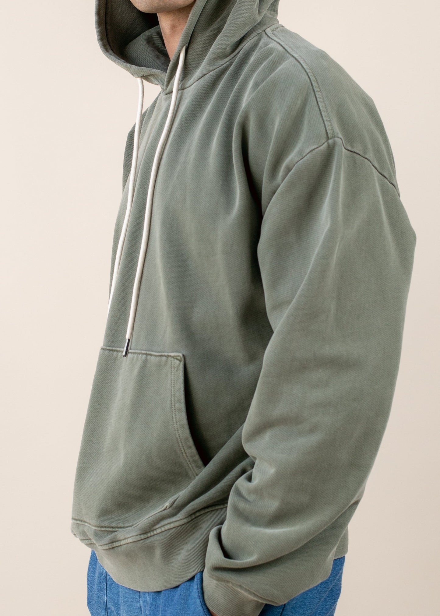 Man in an olive green hoodie with drawstrings and kangaroo pocket, casual men's fashion