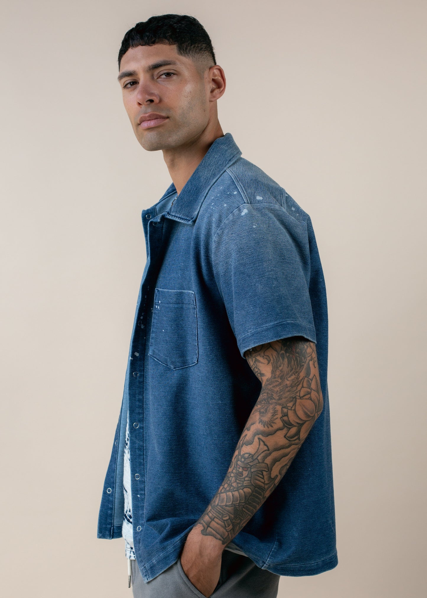 Man modeling blue short-sleeve shirt with tattooed arm, men's fashion lifestyle photo