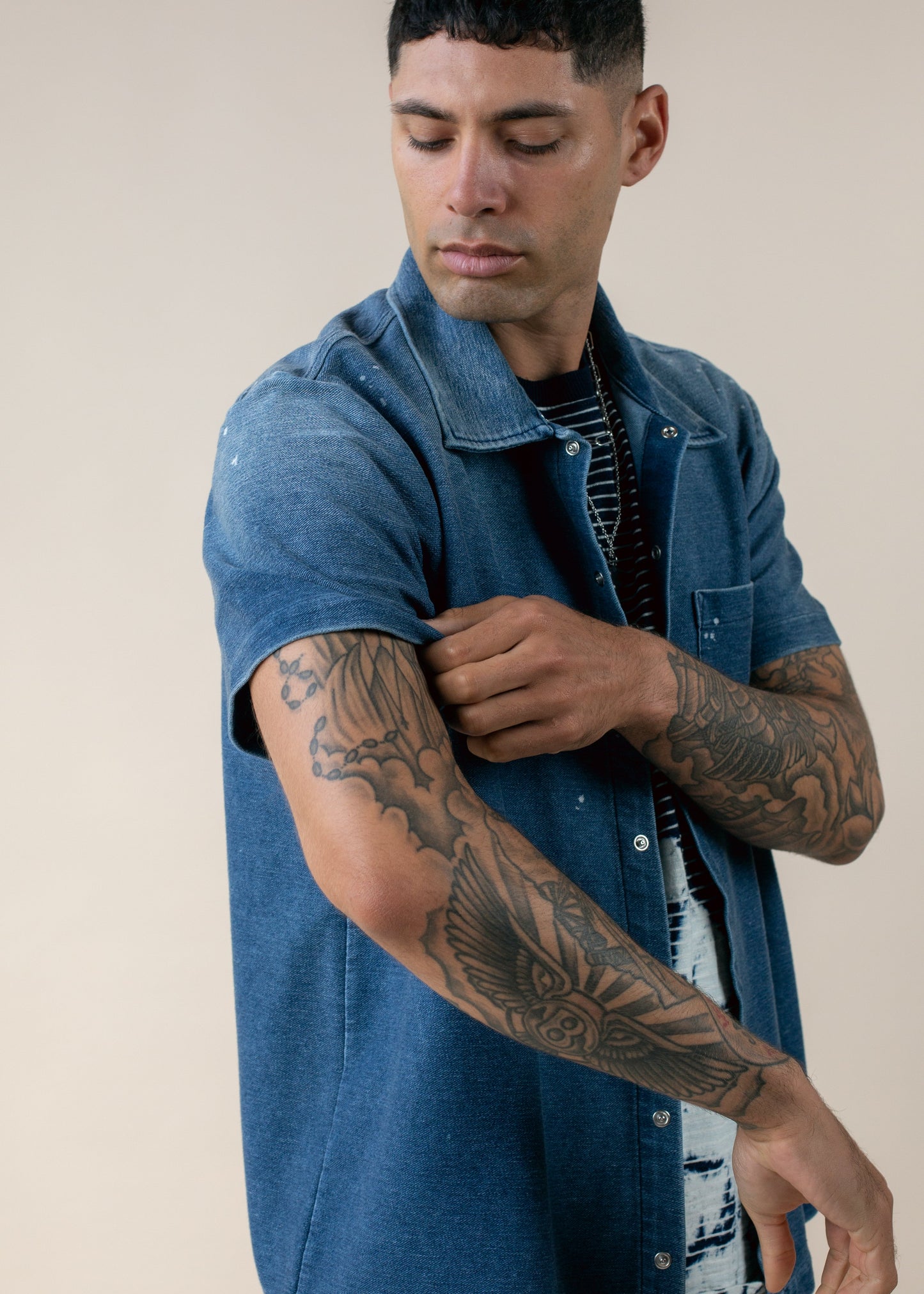 Man in blue short sleeve shirt shows tattooed arm, MANN men's fashion lifestyle