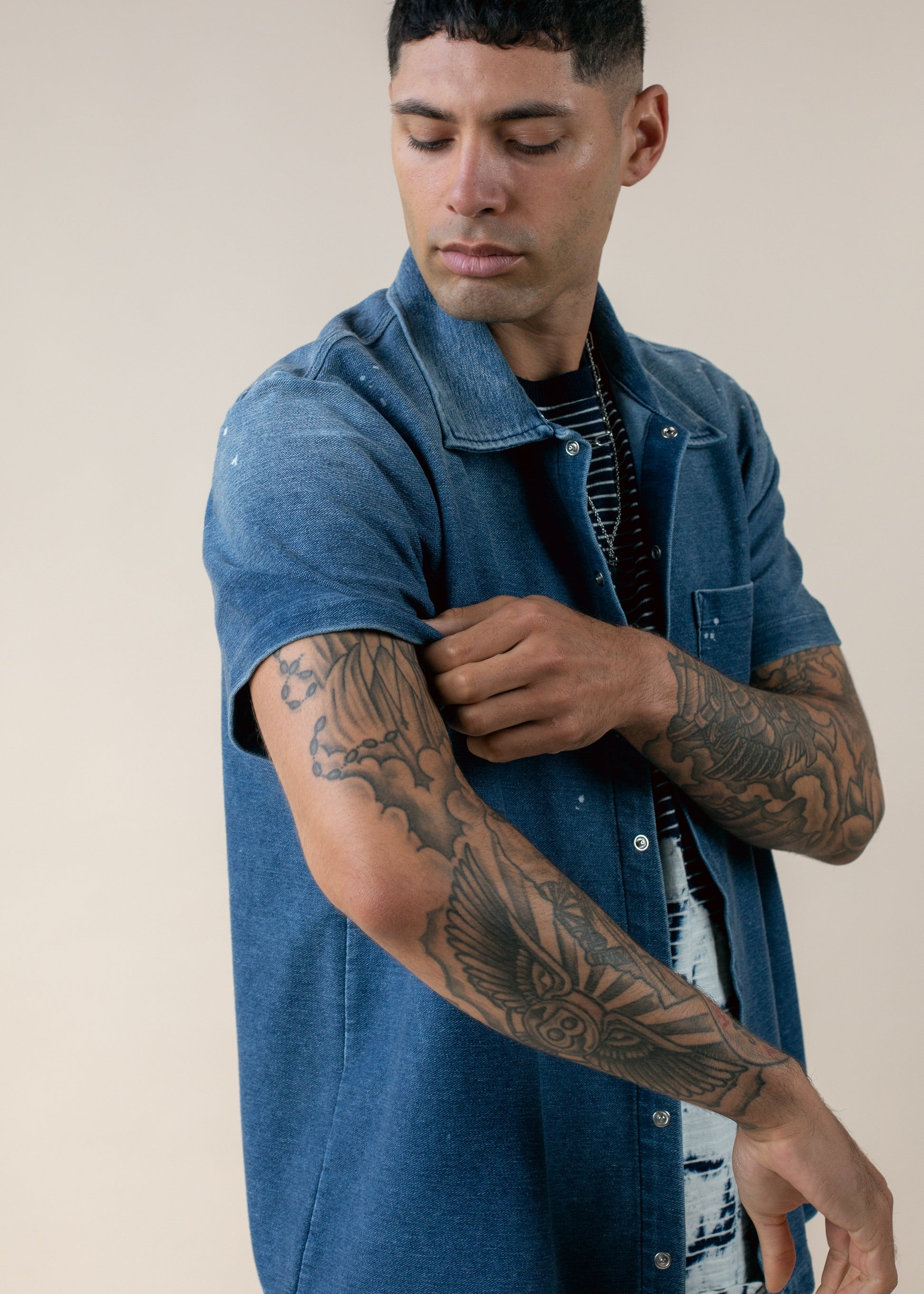 Man in blue short sleeve shirt shows tattooed arm, MANN men's fashion lifestyle