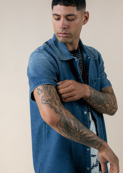 Man in blue short sleeve shirt shows tattooed arm, MANN men's fashion lifestyle