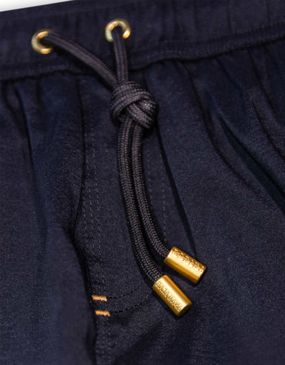 Men's black swimsuit. 6 inch stretch volley trunks. Gold finishes. Functional zipper pockets with internal stash pocket.