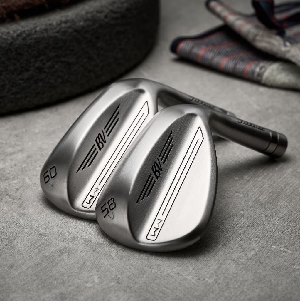 Close-up of two BV golf wedges on a textured surface, featuring MANN men's lifestyle branding.